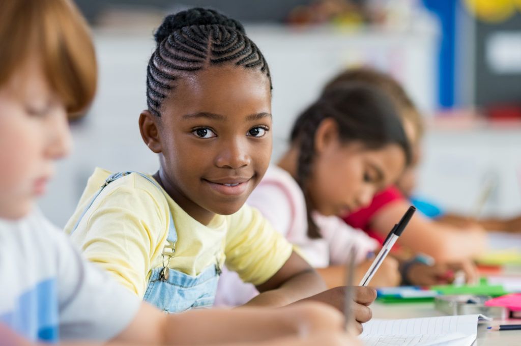 Portrait of young student studying with classmates in background.