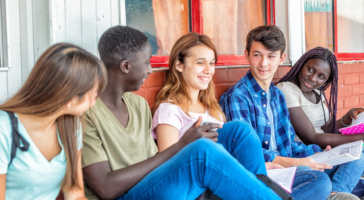 Group of mixed races teenagers at school with notebooks smiling
